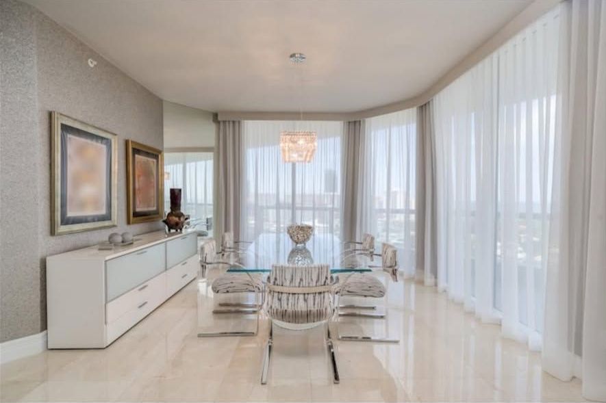 A large dining room with a glass table and chairs.