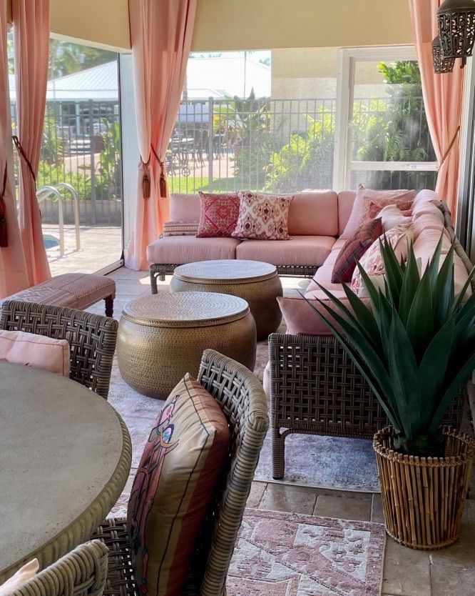 A living room with a couch , table , chairs and a potted plant.