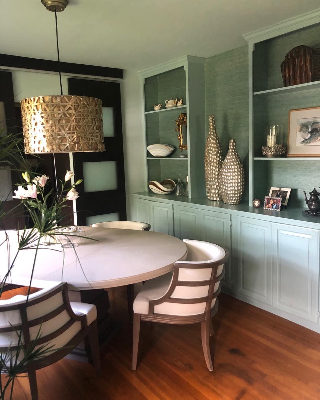 A dining room with a table and chairs and a lamp hanging from the ceiling.