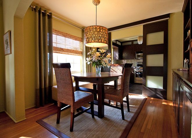 A dining room with a table and chairs and a vase of flowers