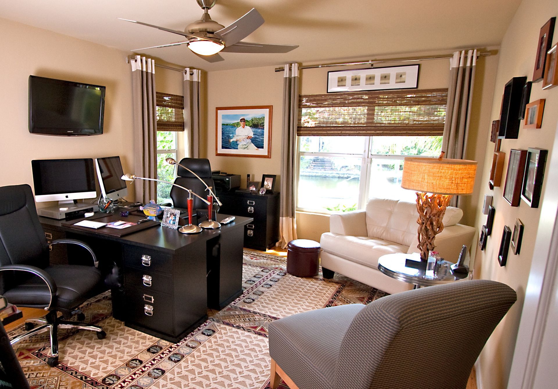 A living room with a desk and chairs and a ceiling fan