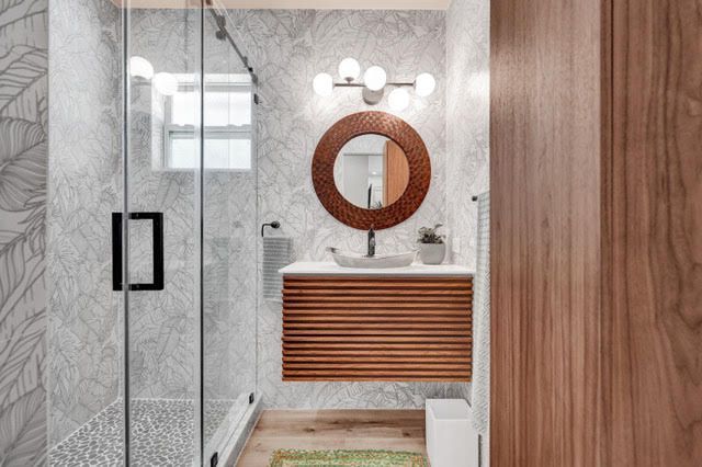 A bathroom with a sink , mirror and walk in shower.