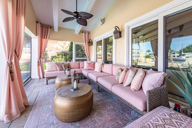 A patio with pink furniture and a ceiling fan.