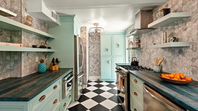 A kitchen with blue cabinets , stainless steel appliances , and a checkered floor.