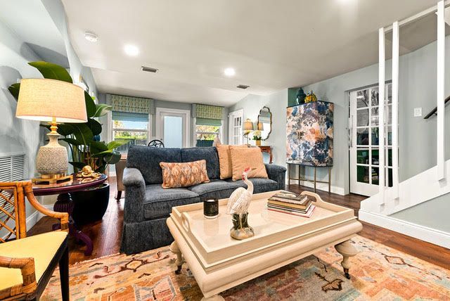 A living room with a couch , coffee table , chairs and stairs.