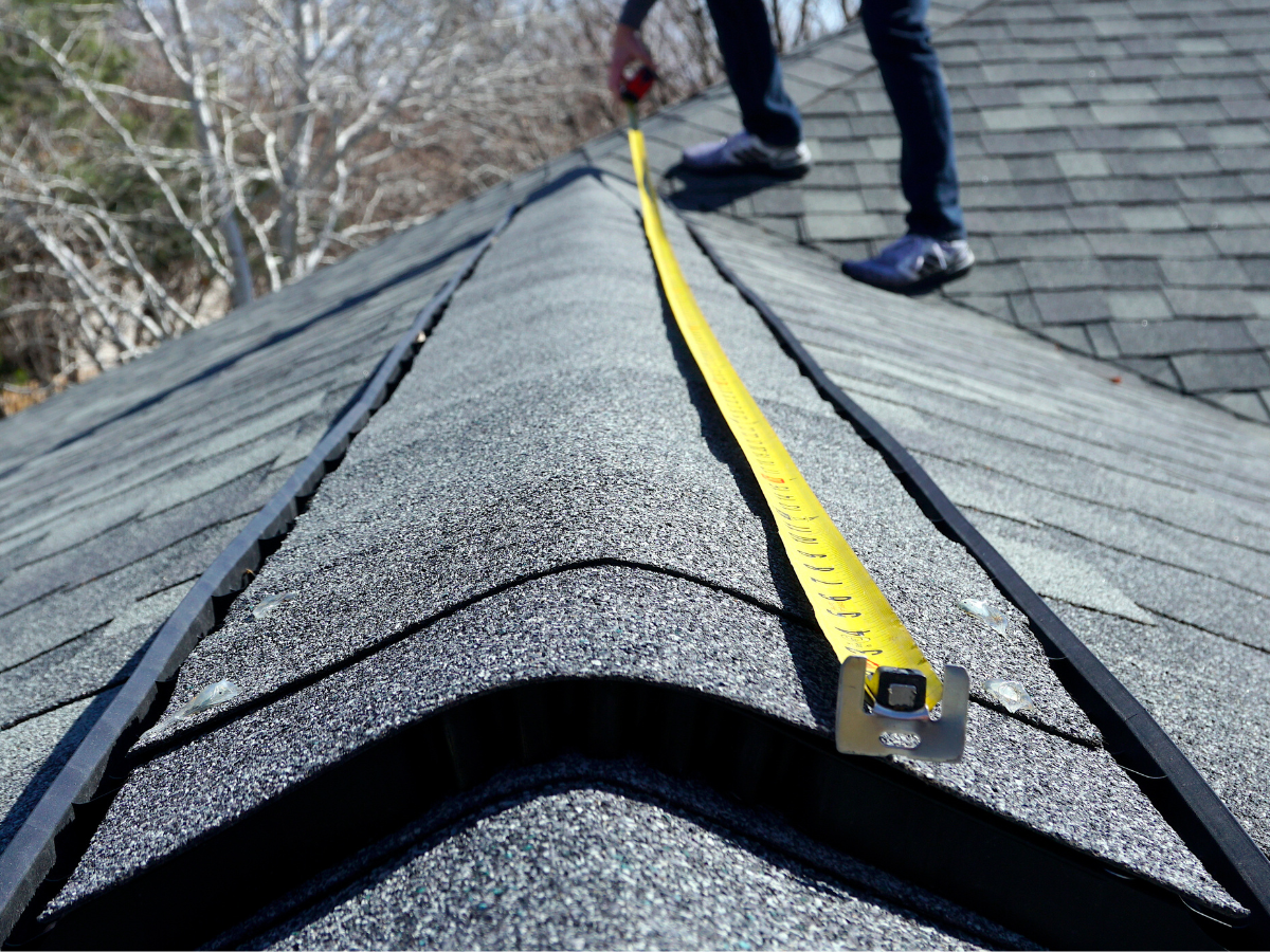 A person measuring a roof with a tape measure A person measuring a roof with a tape measure