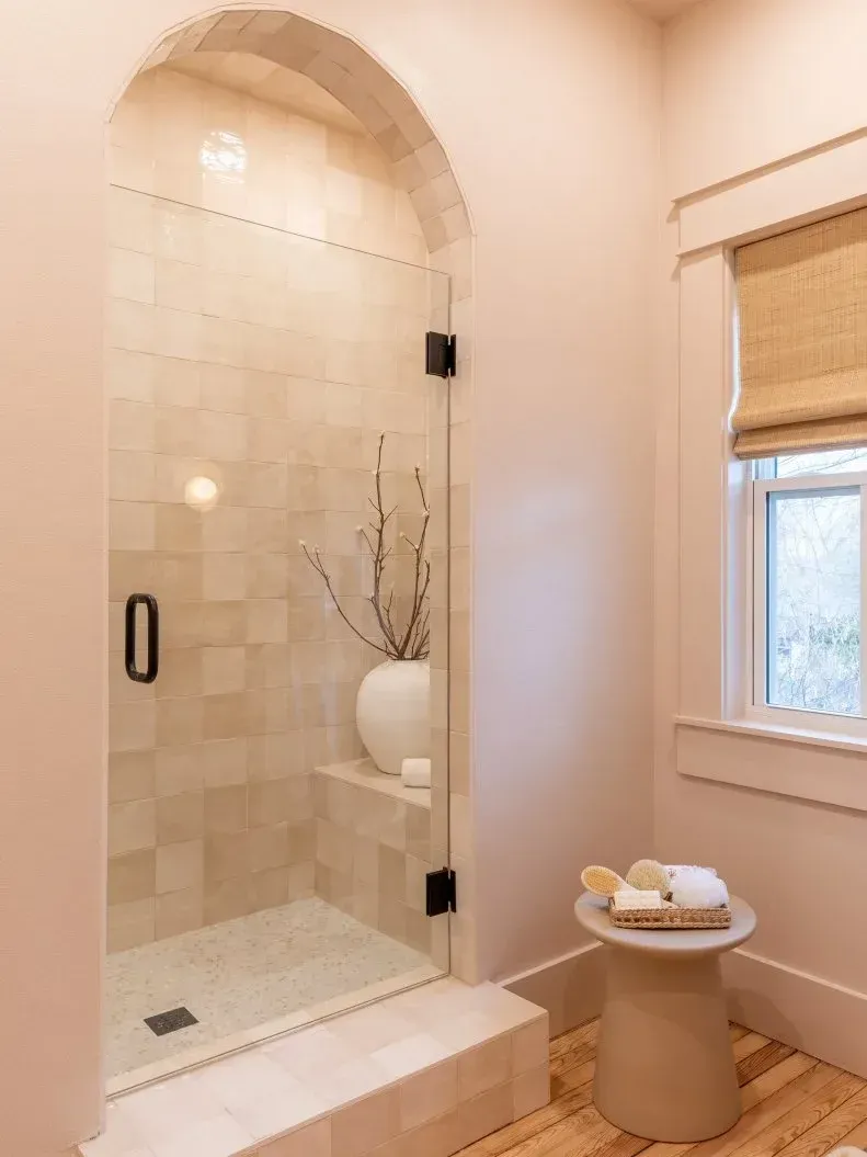 A bathroom with a walk in shower and a window.