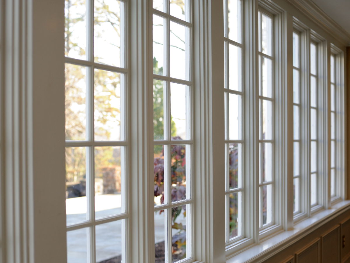 A room with a lot of windows and a reflection of trees in the windows.