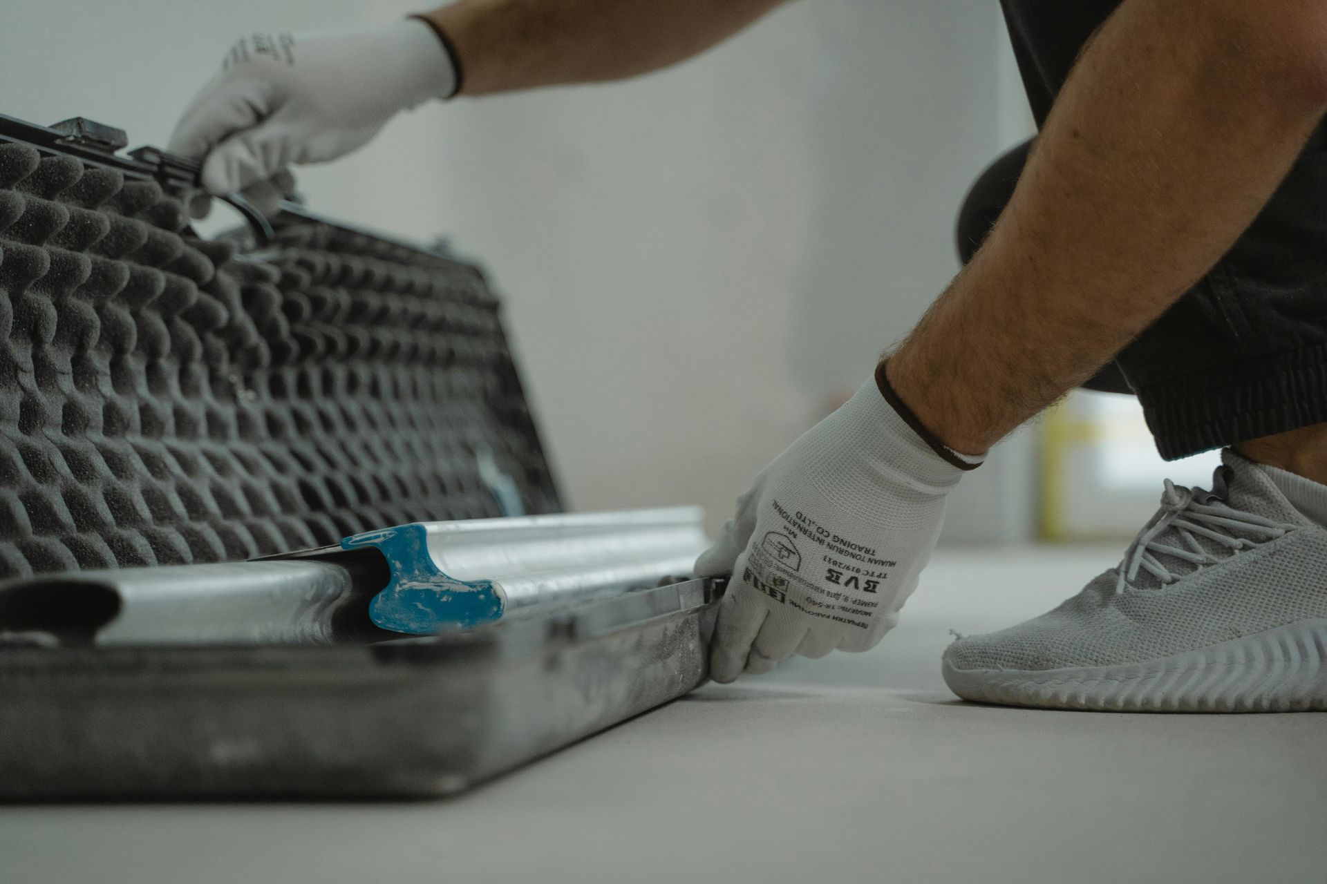 A man is kneeling down on the floor using a trowel.