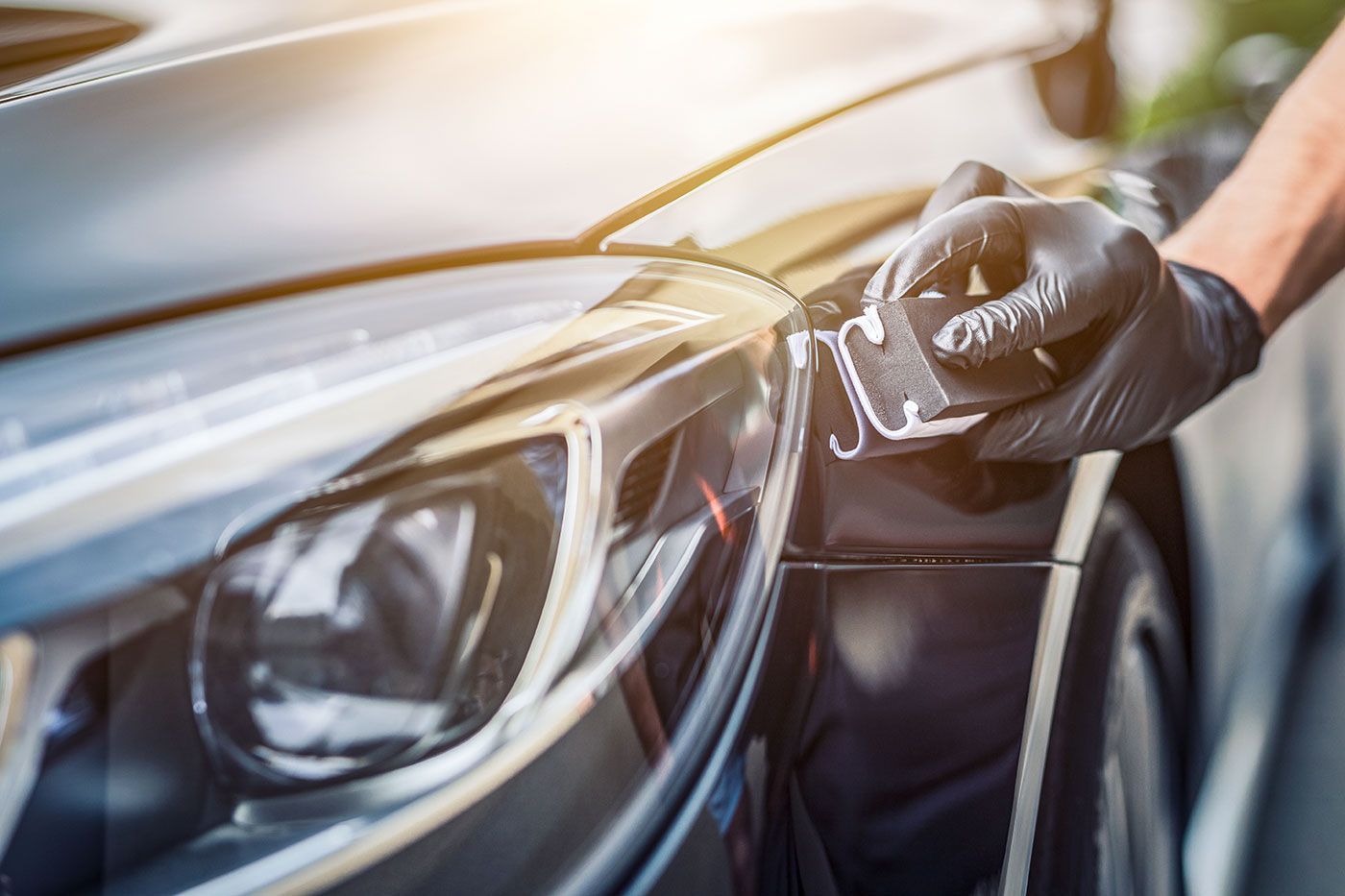 A person is polishing the headlight of a car.