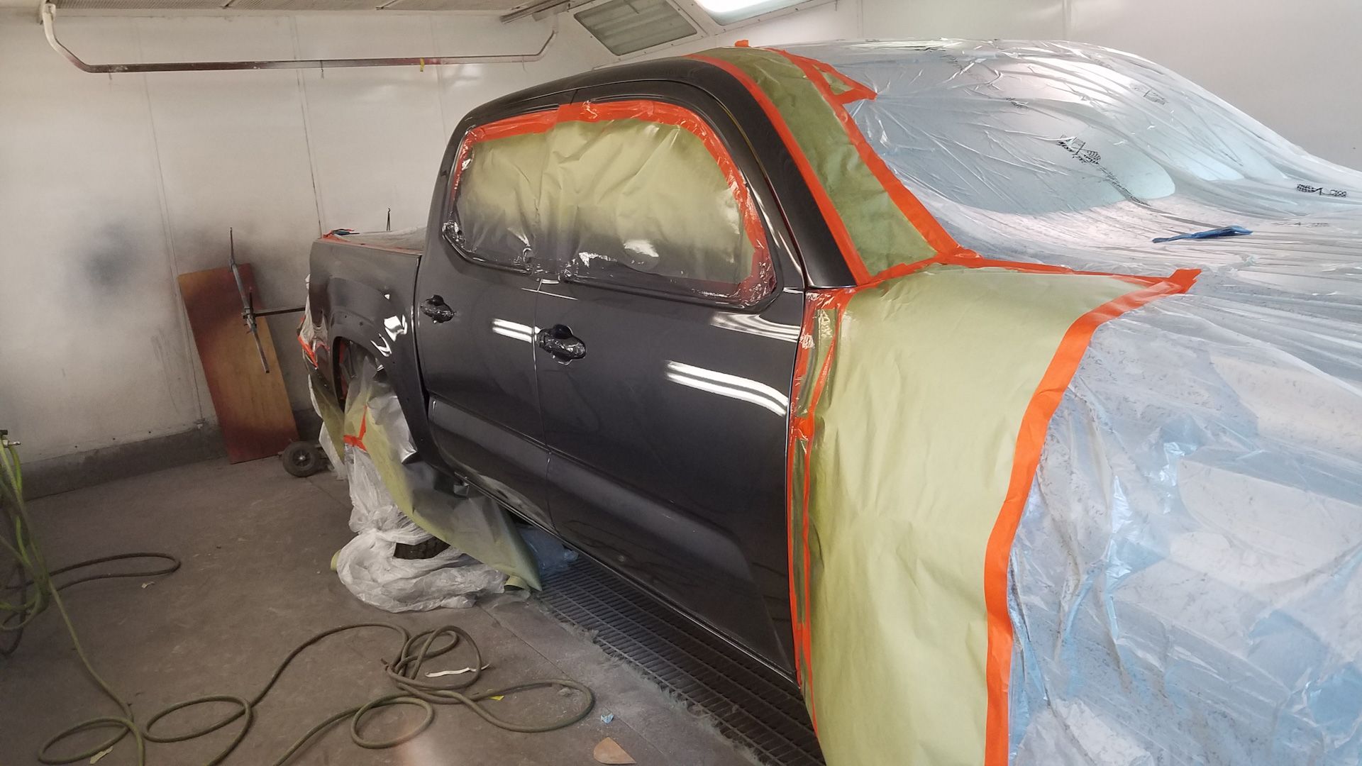 A black truck is being painted in a garage.