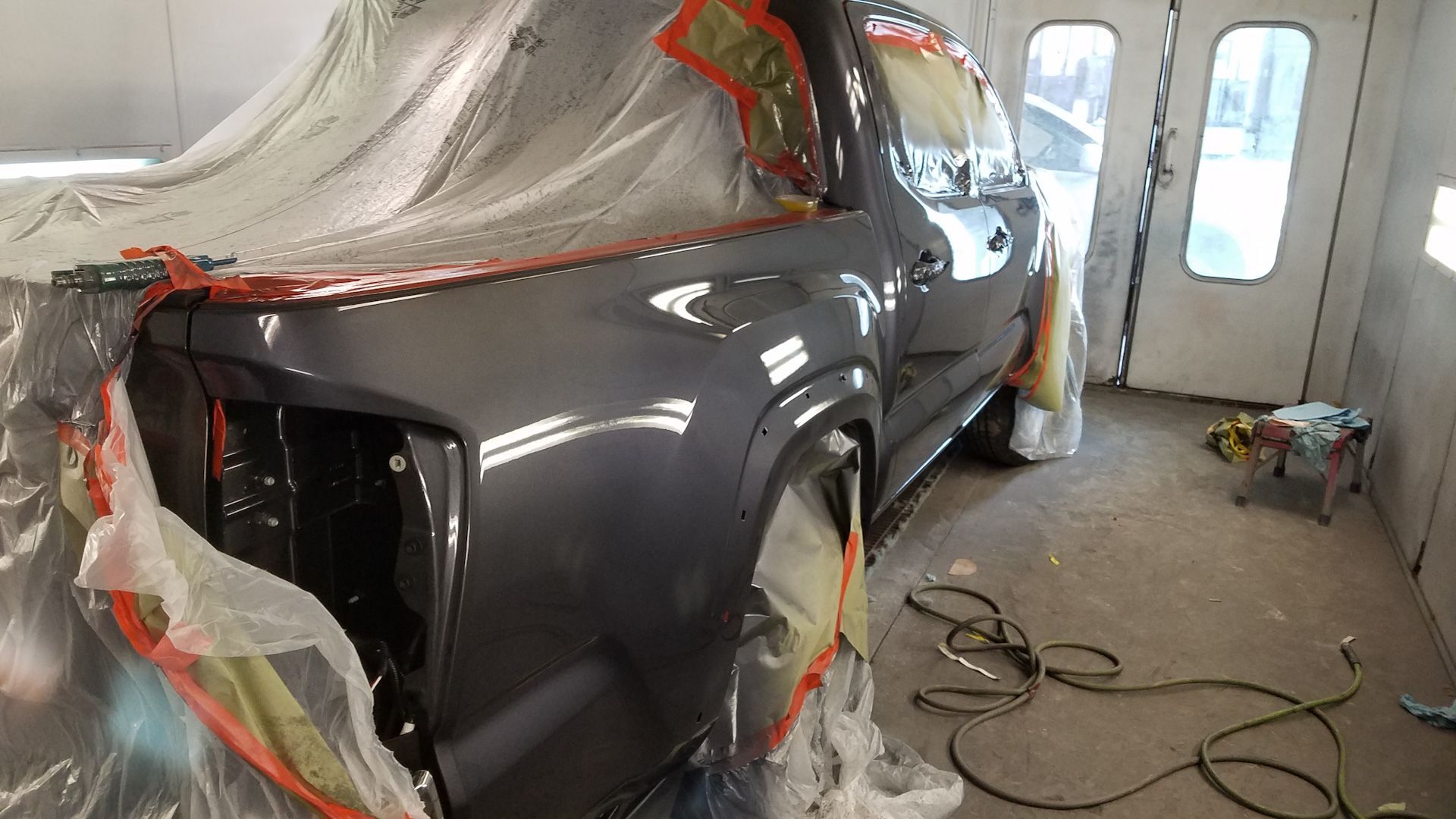 A truck is being painted in a paint booth.
