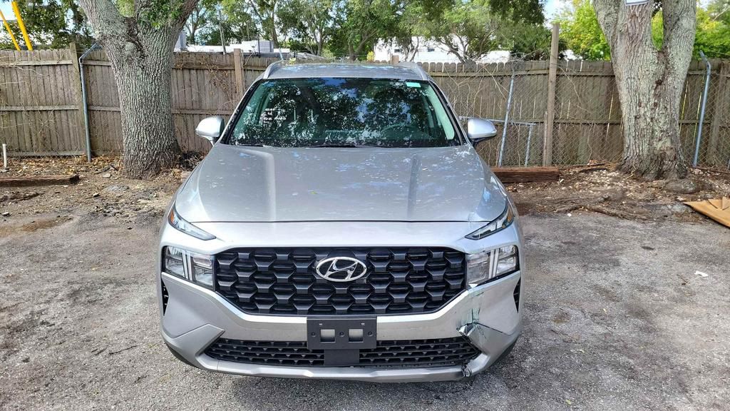 The front of a silver hyundai santa fe is parked in a parking lot.