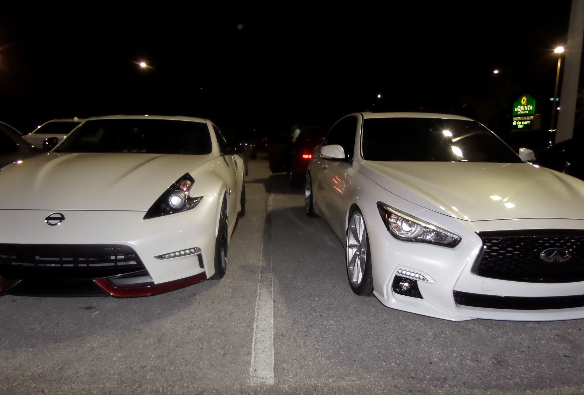 Two white cars are parked next to each other in a parking lot