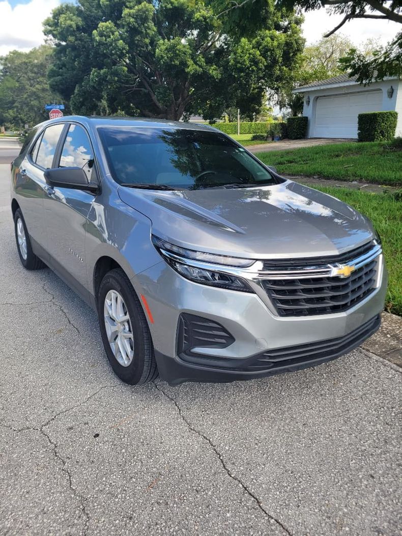 A silver chevrolet equinox is parked on the side of the road.