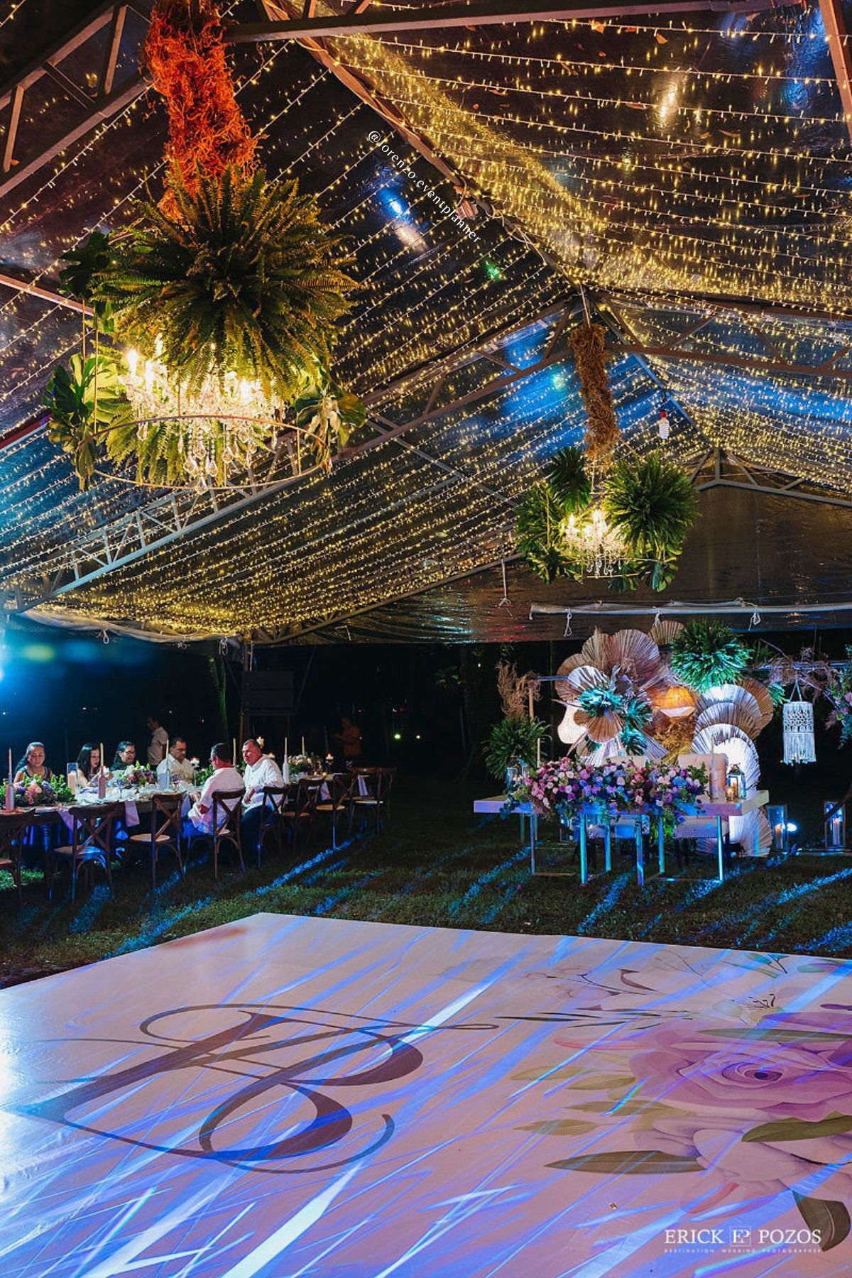 Una recepción de boda bajo una carpa transparente con pista de baile.