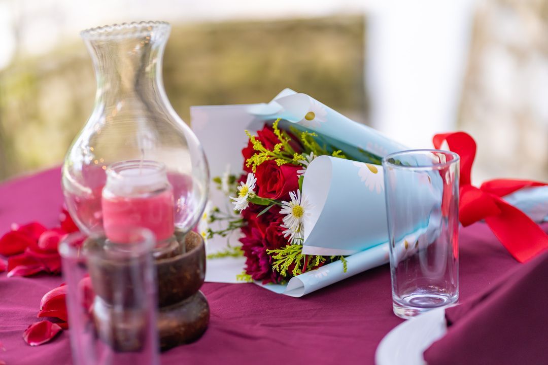 Un ramo de flores está sobre una mesa al lado de un jarrón y un vaso.