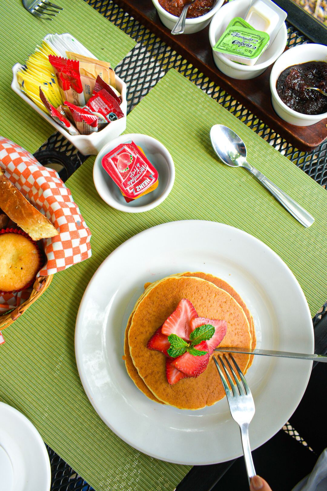 Un plato de panqueques con fresas y un tenedor sobre una mesa.