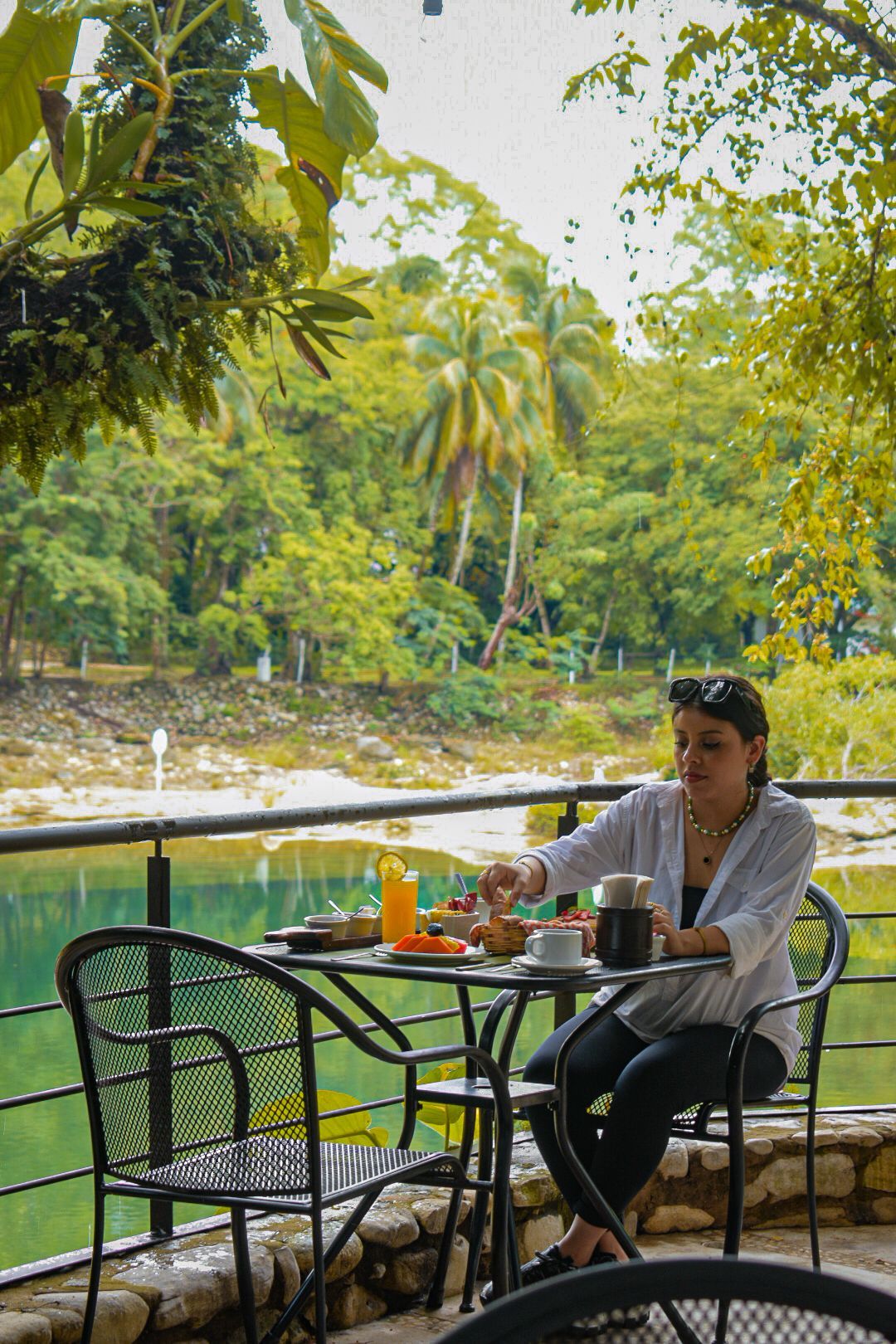Una mujer está sentada en una mesa con vistas a un lago.
