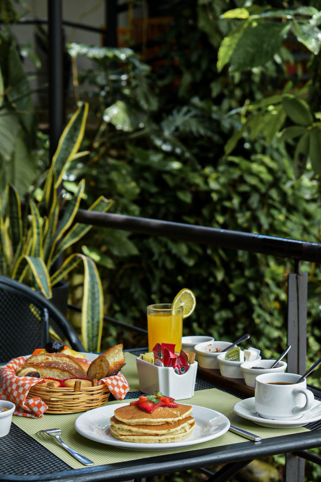 Una mesa cubierta de panqueques, fruta, jugo y café.