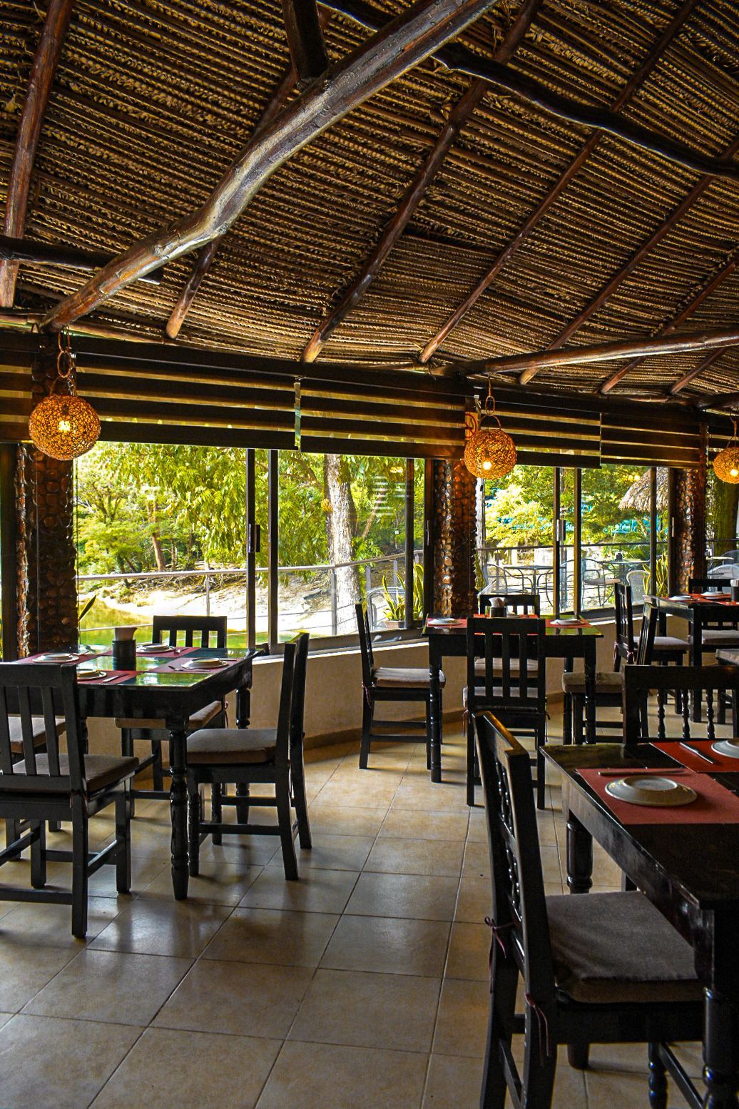 Un restaurante con mesas y sillas y techo de paja.