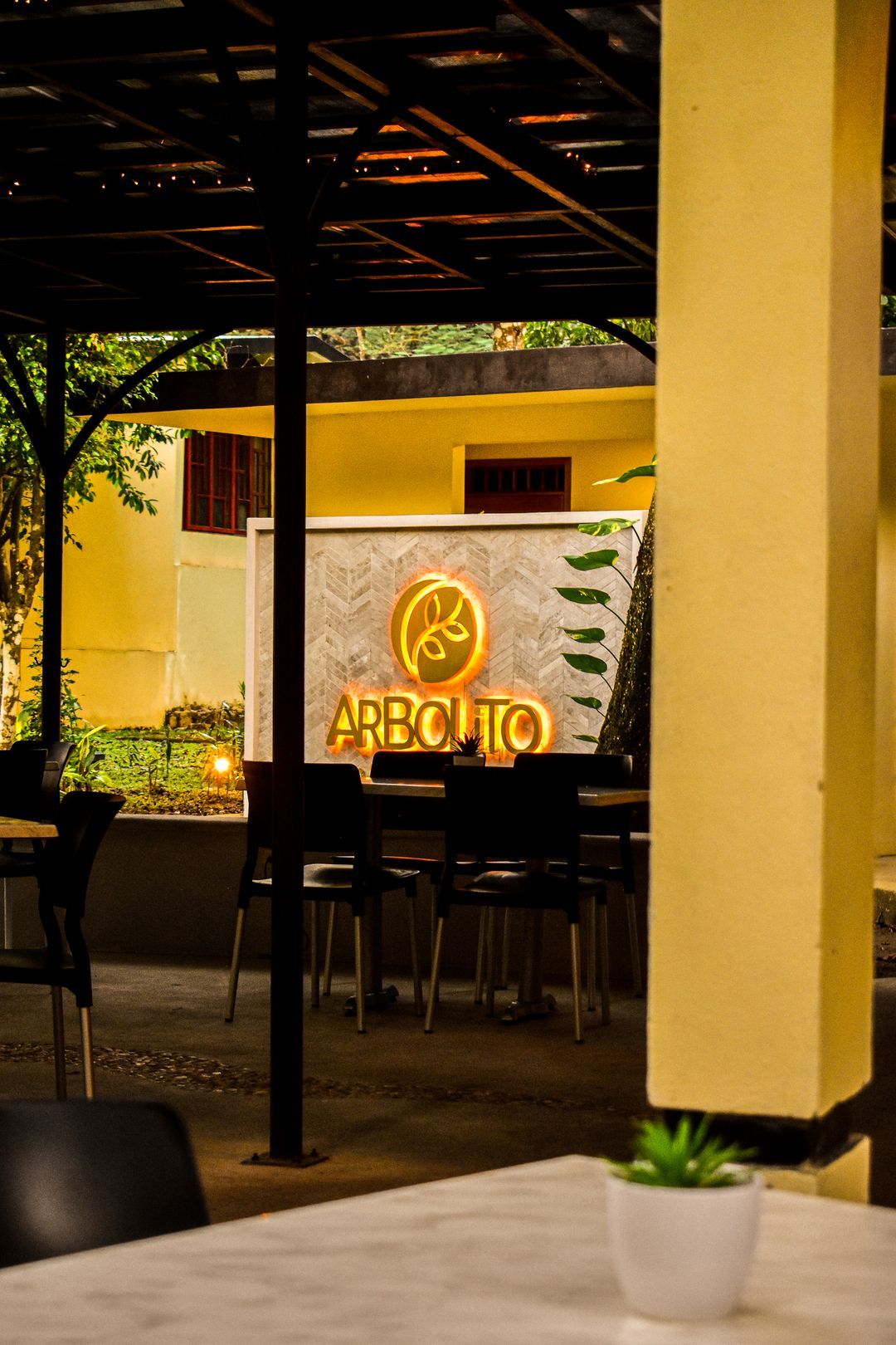 Un restaurante con mesas y sillas y una planta en maceta sobre la mesa.