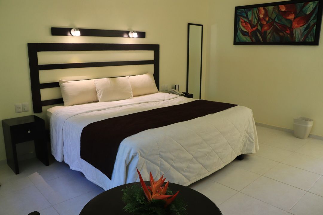 Una habitación de hotel con una cama tamaño king y una mesa con flores.