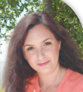 אישה עם שיער חום ארוך לובשת חולצה כתומה ומחייכת.