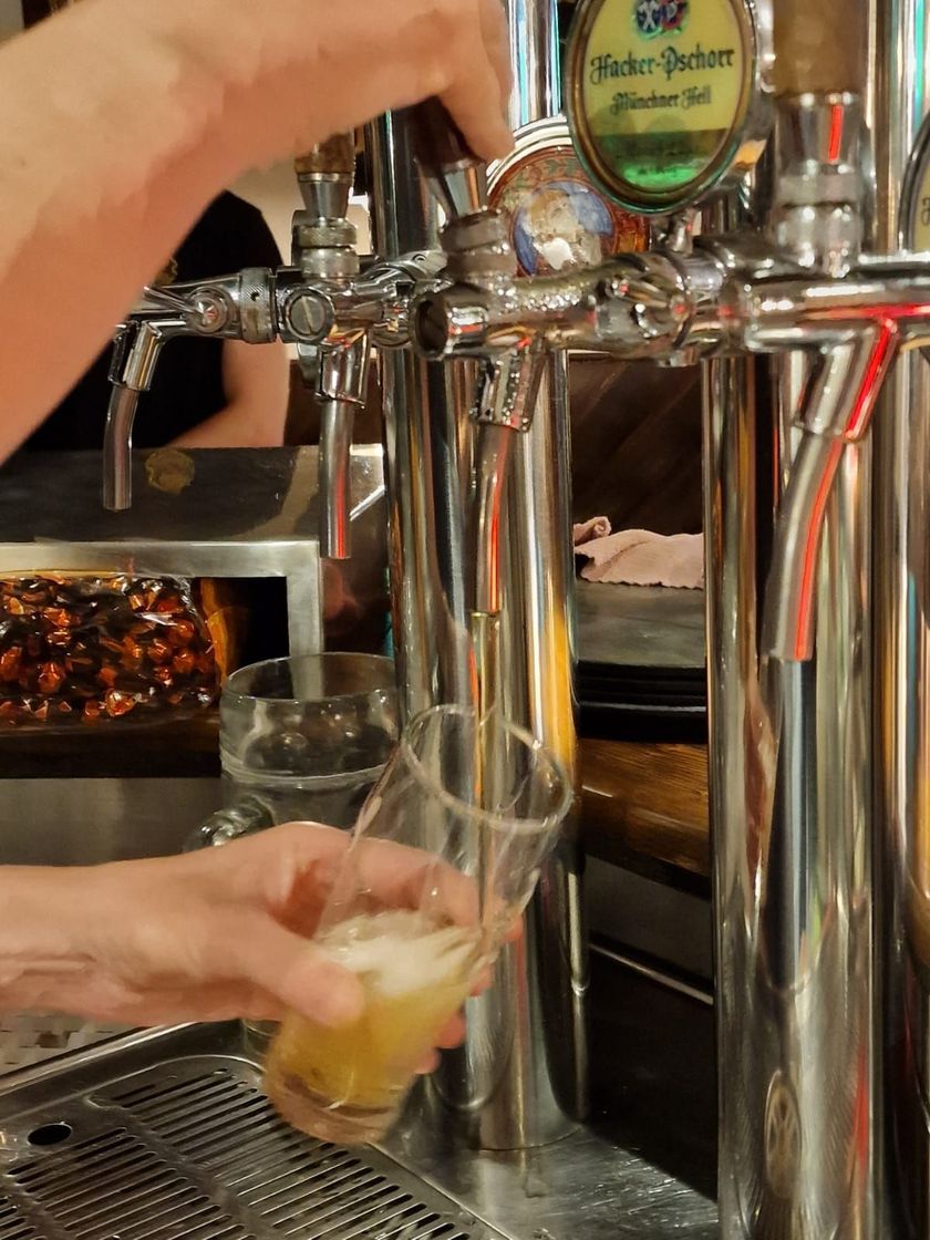 Persona che versa la birra dalla spina in un bicchiere in un bar.