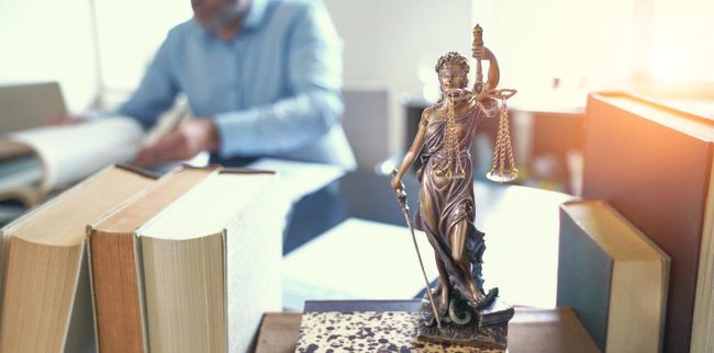 A statue of justice is sitting on a table next to a stack of books.