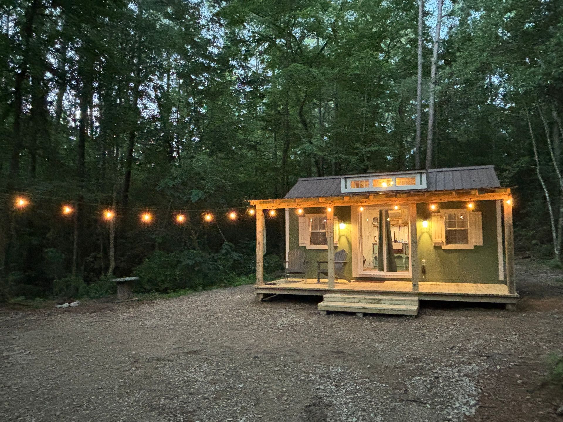 A small house with a porch in the middle of a forest.