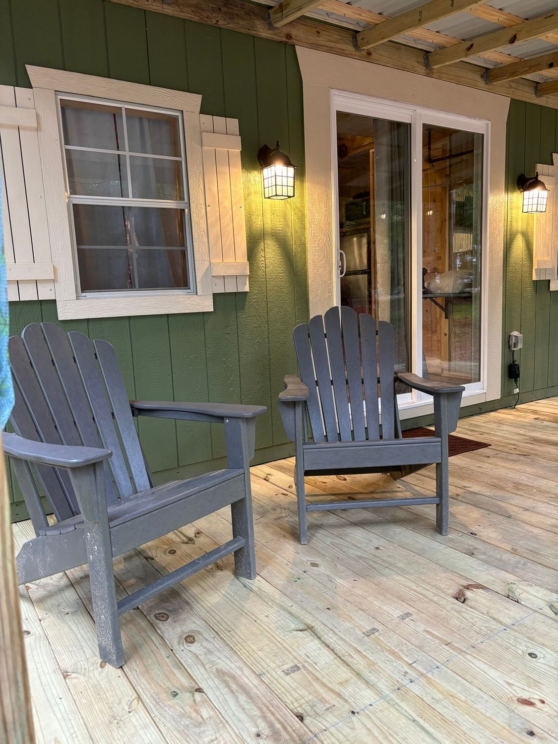 Two chairs are sitting on a wooden deck in front of a house.