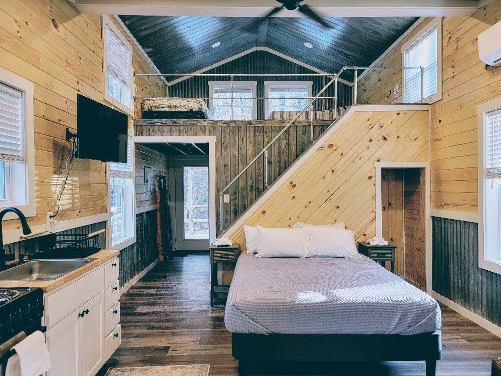 There is a bed in the middle of the room in a small house.