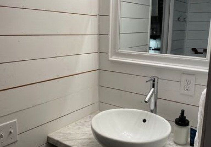 A bathroom with a sink , mirror and soap dispenser.
