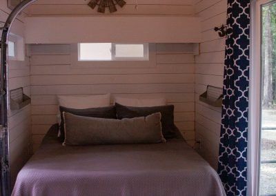 A bed is sitting in a small room next to a window.