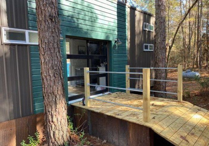 A wooden deck is sitting in front of a house in the woods.