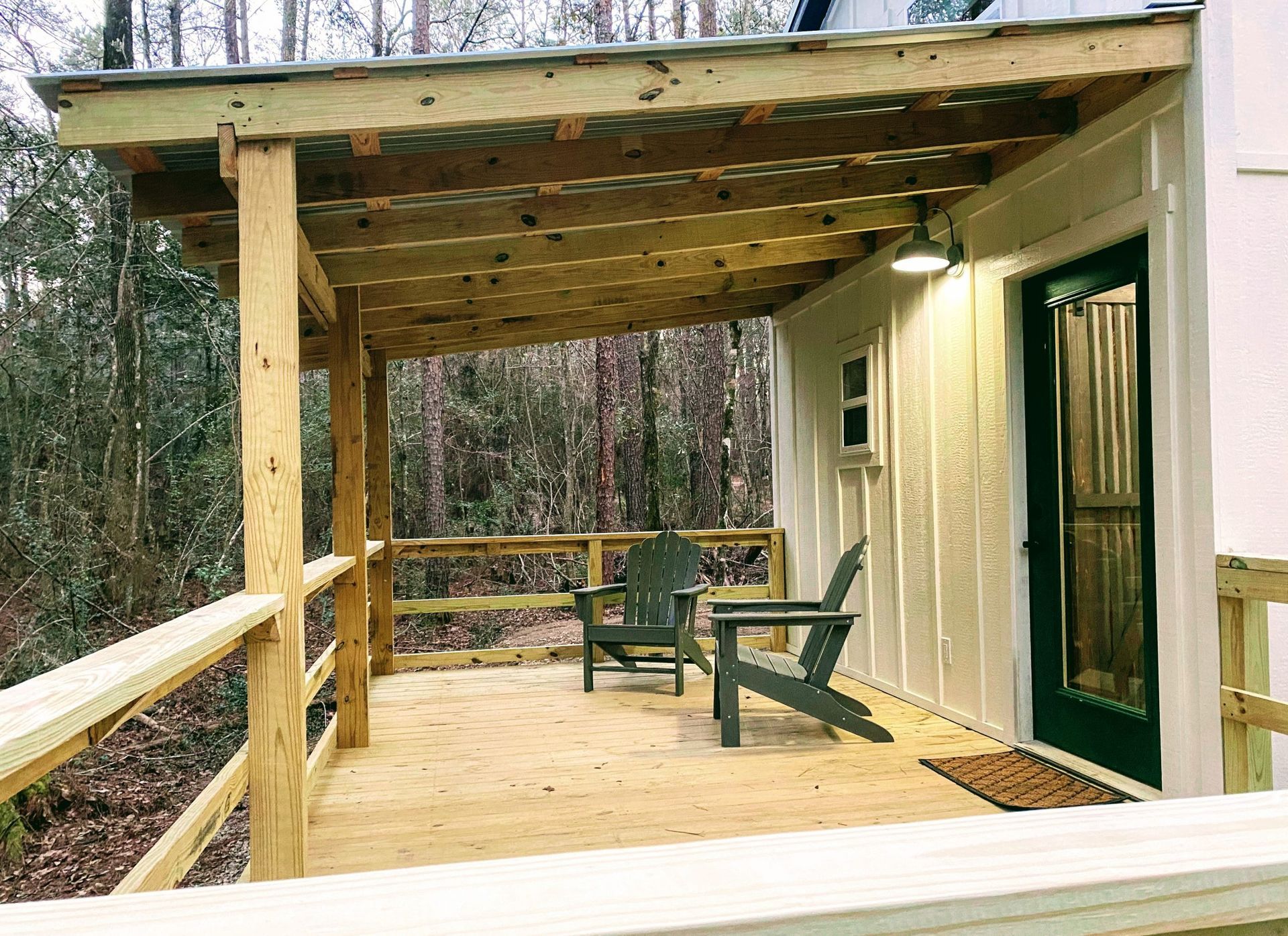 There are two chairs on the porch of a house.