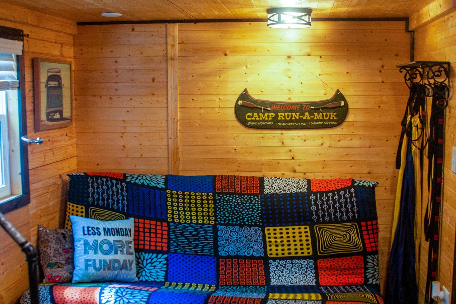 A couch with a colorful blanket and pillows in a wooden room.