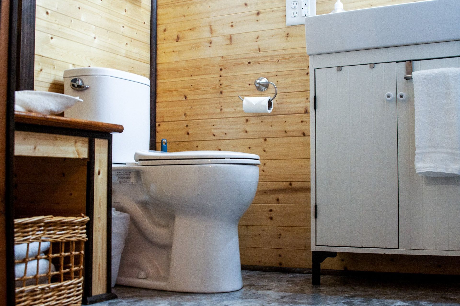 A bathroom with a toilet , sink , and wooden walls.