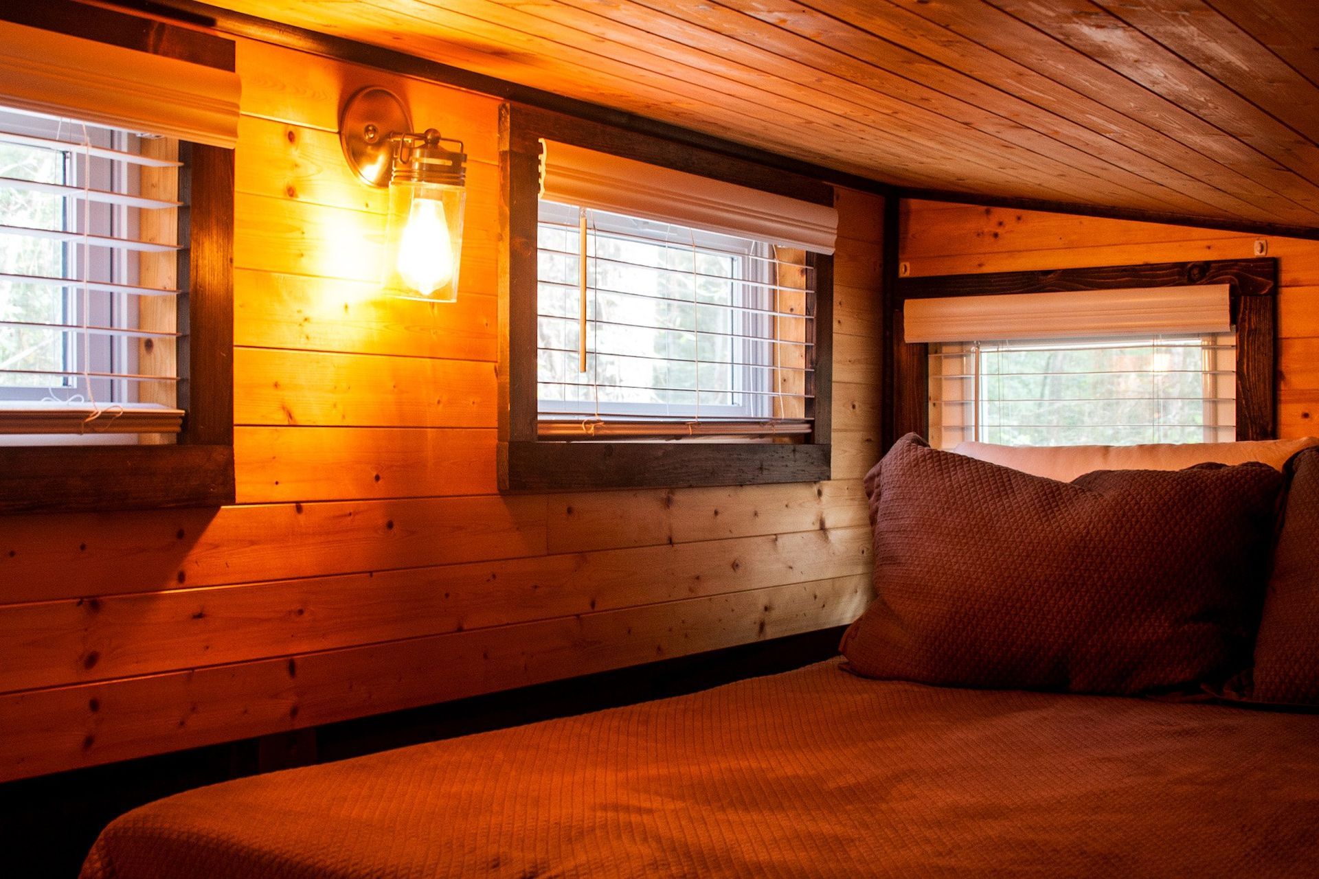 There is a bed in the attic of a wooden house.