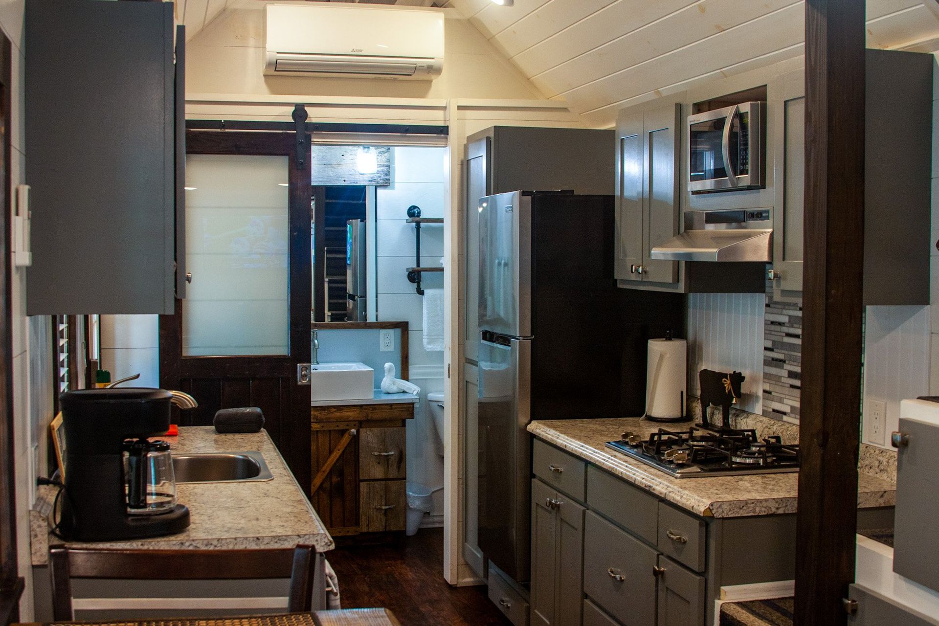 A kitchen with a sink , stove , refrigerator and microwave.