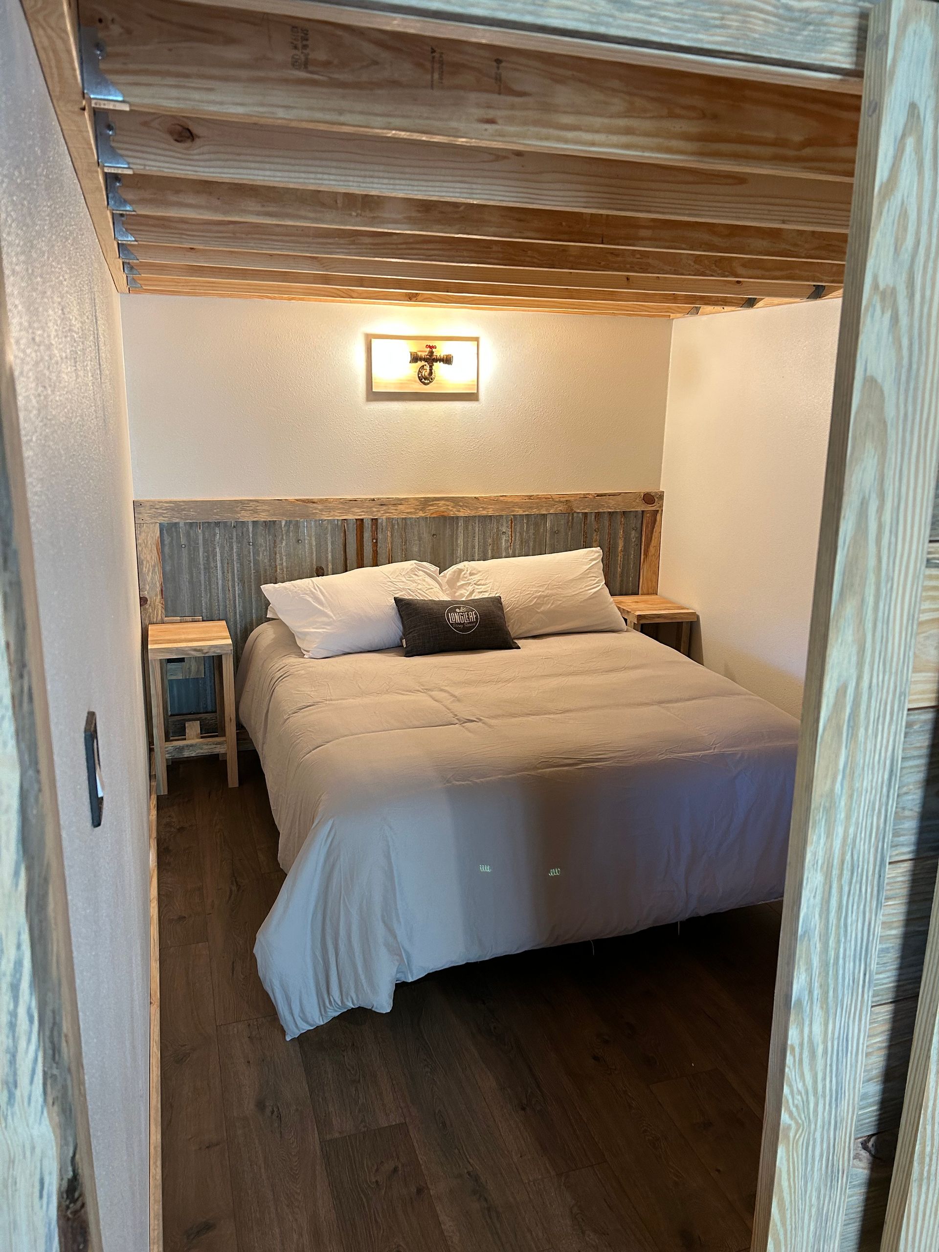 A bedroom with a bed , nightstands , and a wooden ceiling.