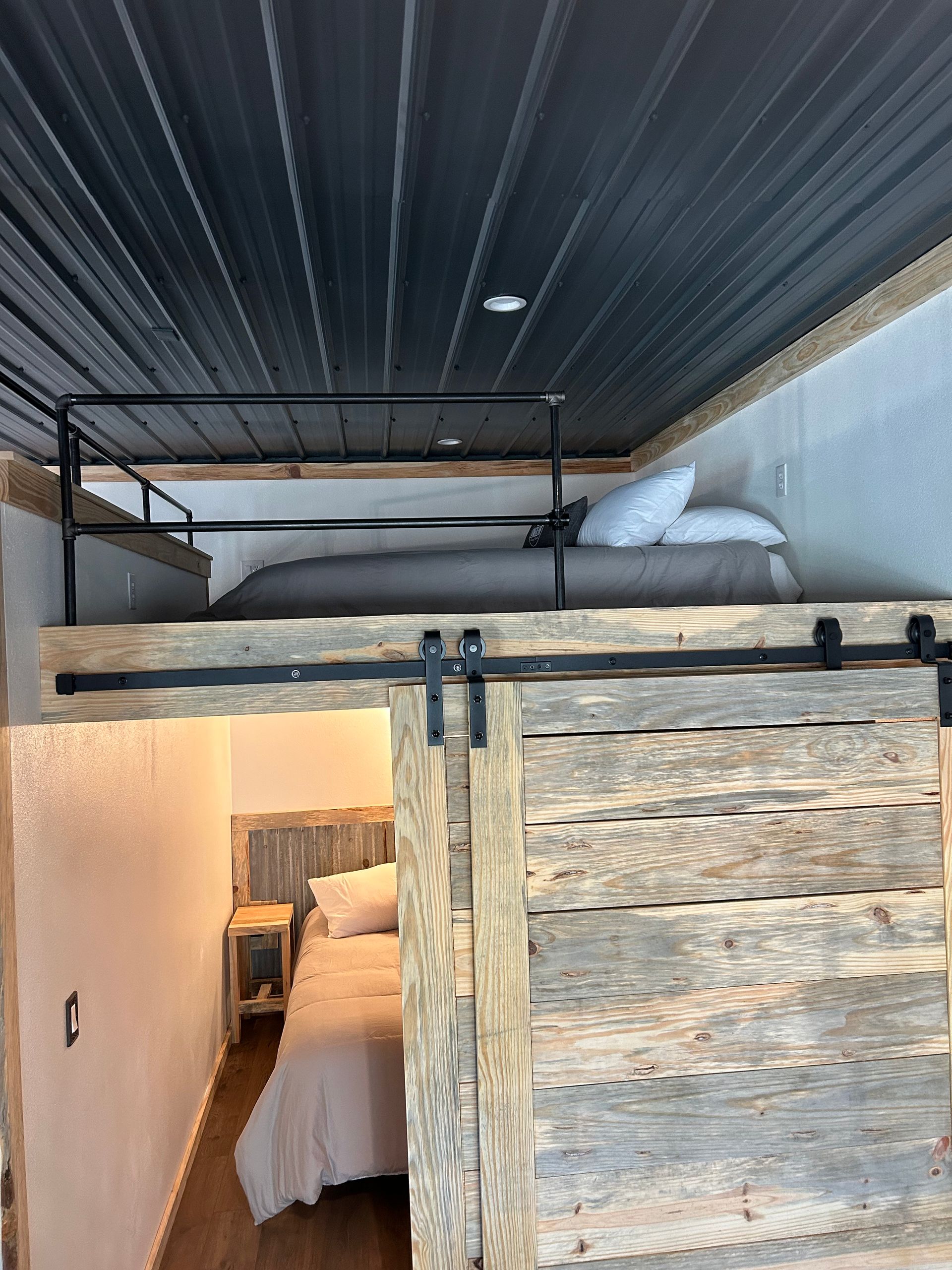 A bedroom with a bunk bed and a sliding barn door.