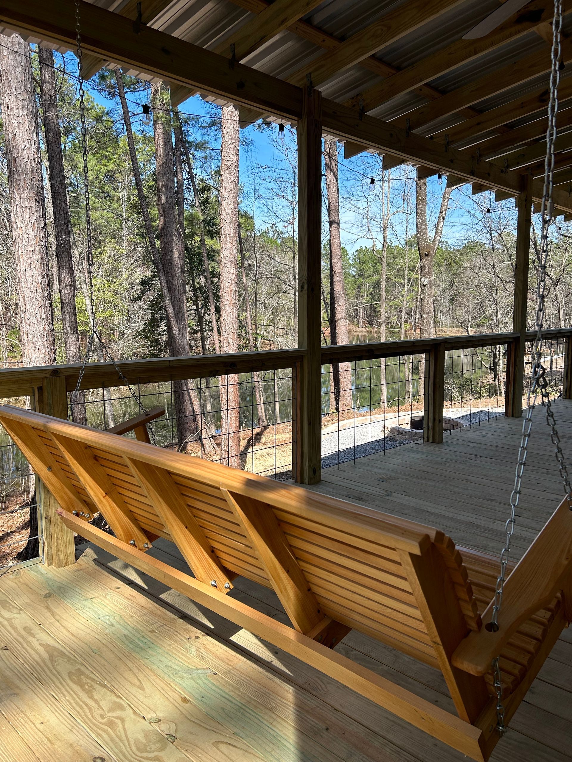 A wooden porch swing with a view of the woods.
