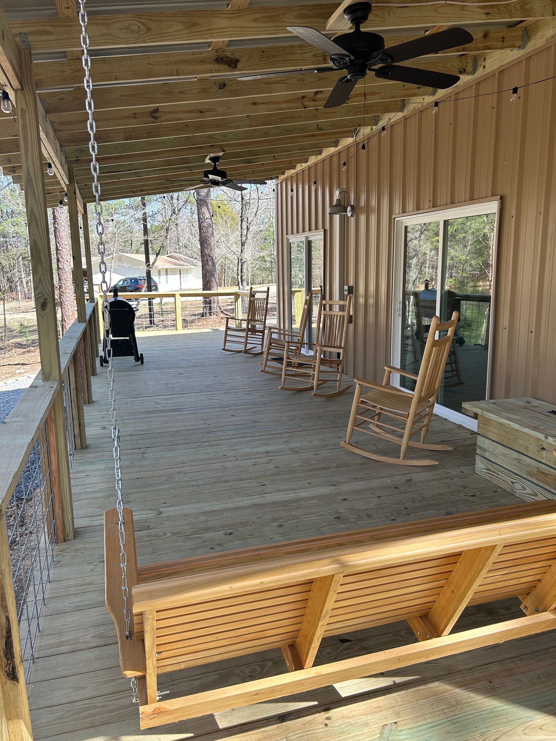 A wooden porch with rocking chairs and a ceiling fan.