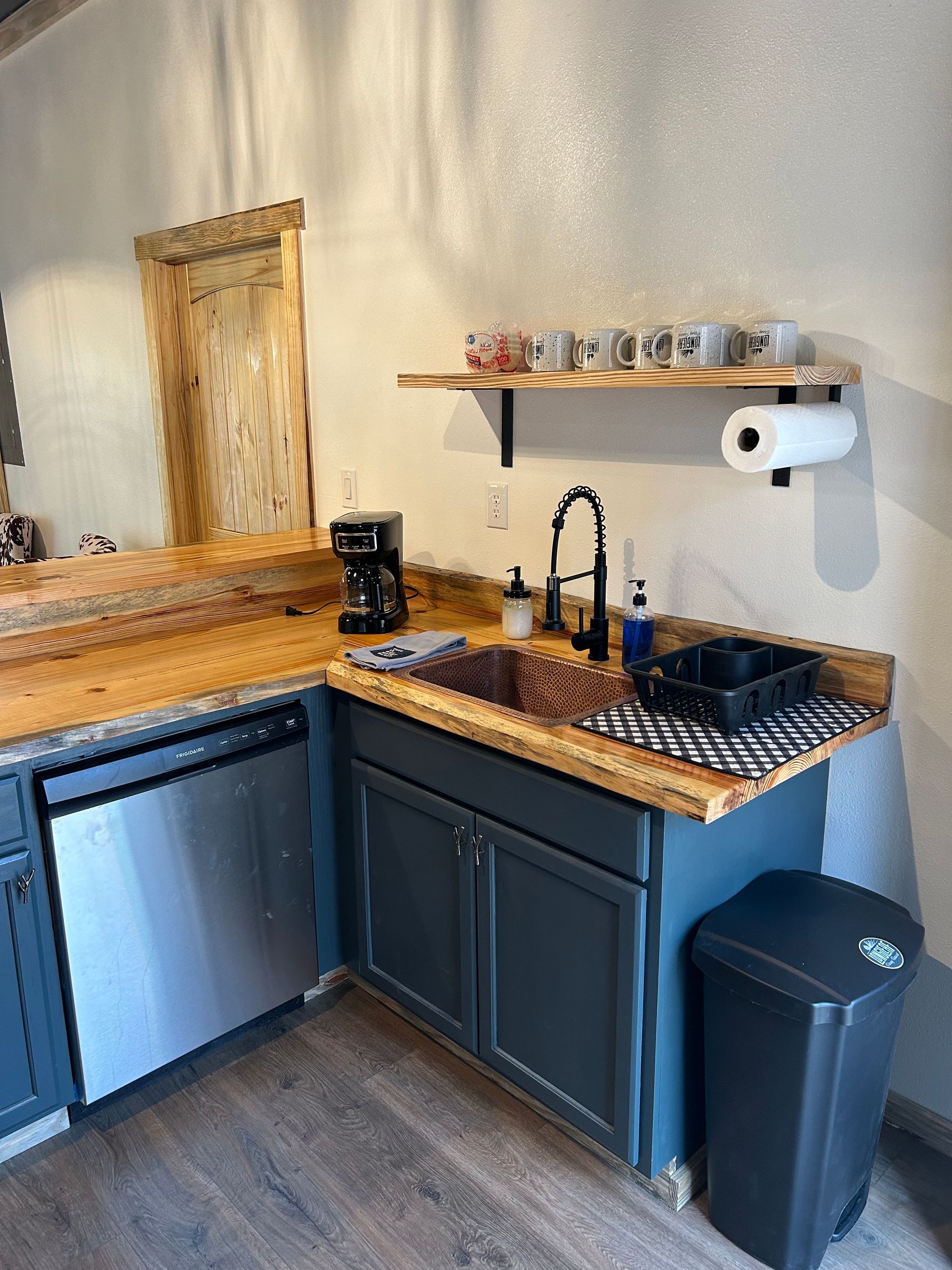 A kitchen with a sink , dishwasher , and trash can.