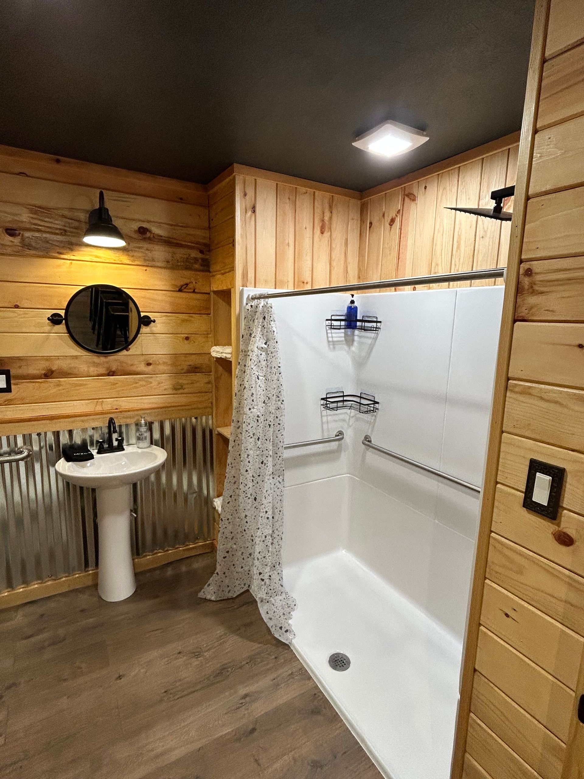A bathroom with a sink , shower , and mirror.