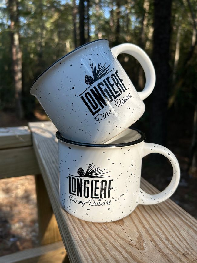 Two coffee mugs are stacked on top of each other on a wooden rail