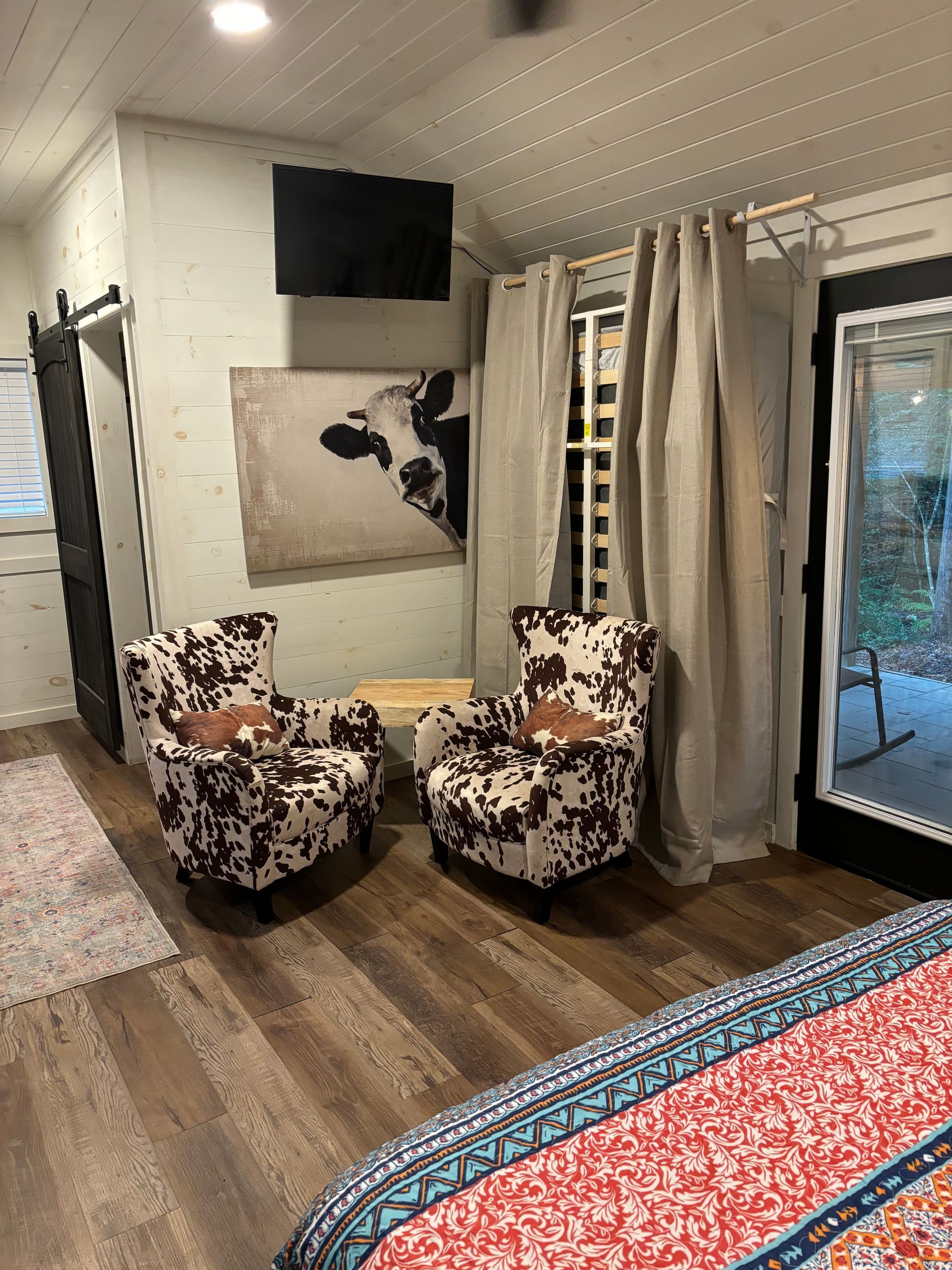 A bedroom with two chairs and a painting of a cow on the wall.