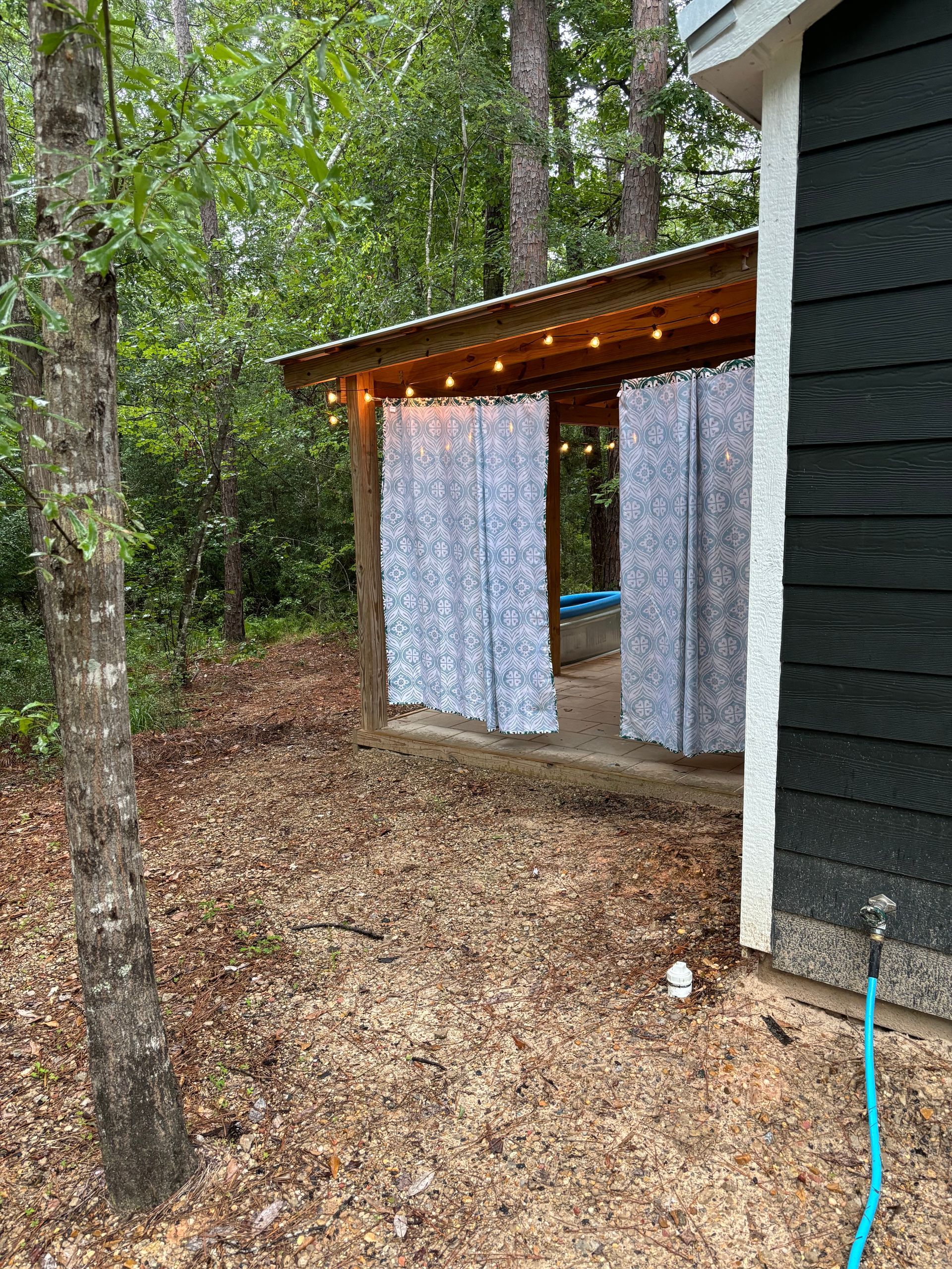 There is a hose next to a house in the woods.